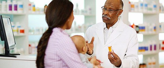 Pharmacist talking with mom holding baby