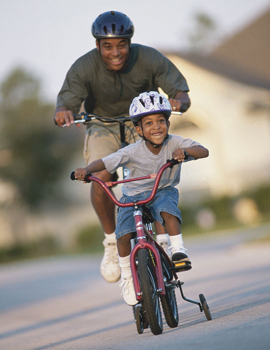 african-american father riding bikes with son