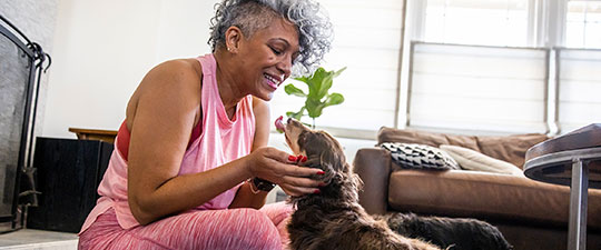 Smiling senior woman sitting on the floor with her dog