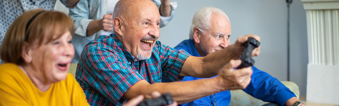 Three seniors laughing while playing video games.